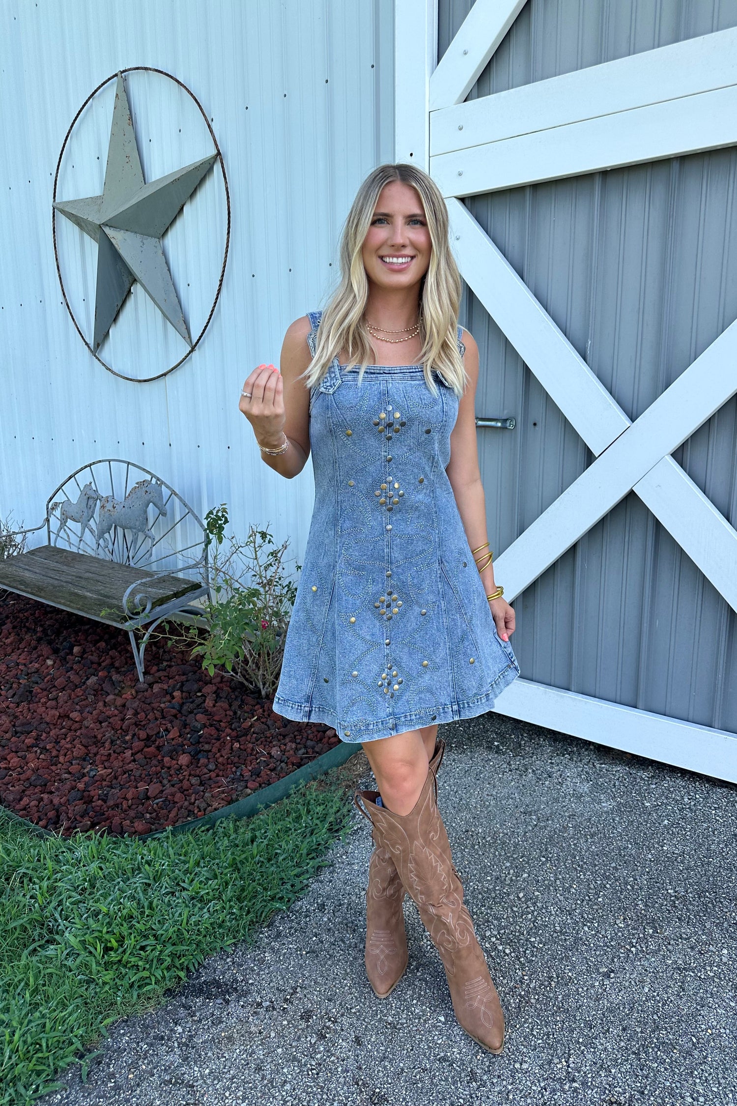 Woman in a blue dress with floral patterns standing in front of a white building with a star design.