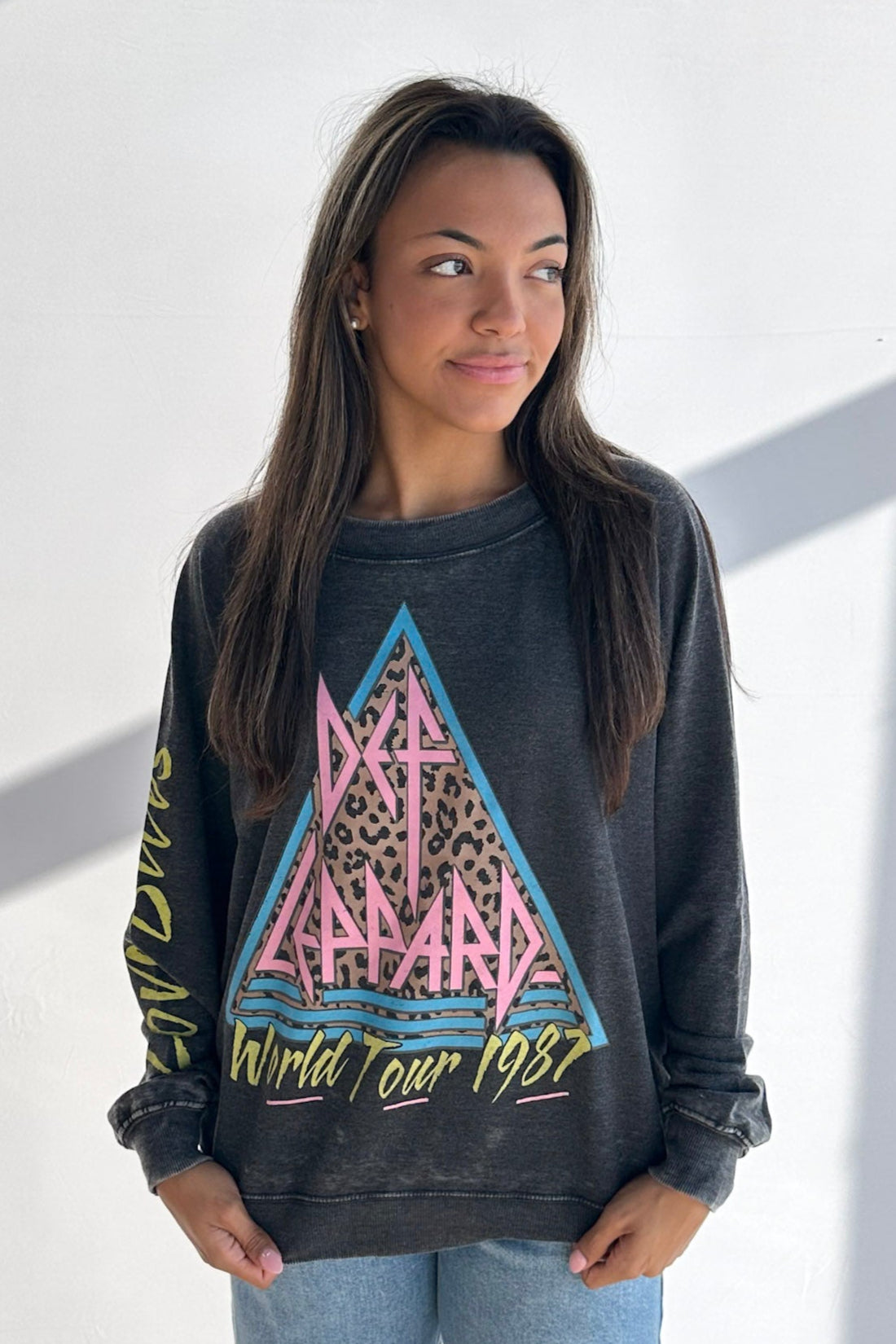 Woman wearing a dark gray sweatshirt with a colorful graphic design on a white background