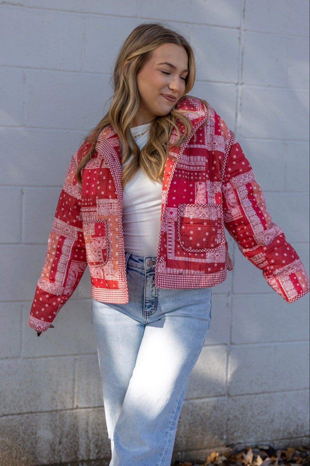 Woman wearing a red and white patterned jacket against a light gray wall.
