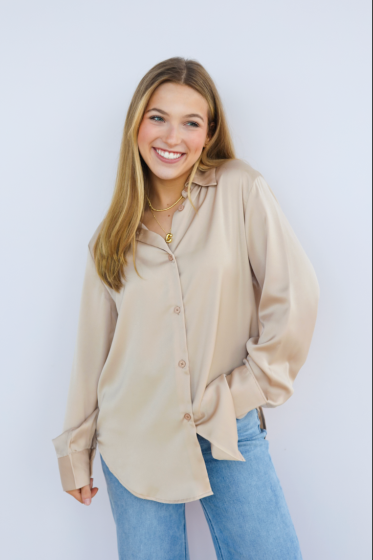 Woman wearing a beige blouse and blue jeans against a white background