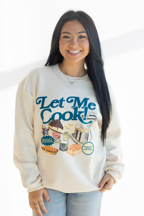 Woman wearing a cream sweatshirt with 'Let Me Cook!' graphic design on a white background