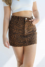 Person wearing a leopard print skirt on a white background
