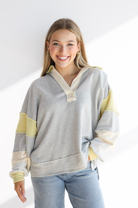 Woman wearing a gray and yellow striped sweater with a white background