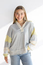 Woman wearing a gray and yellow striped sweater with a white background