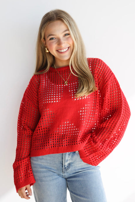 Woman wearing a red sweater and blue jeans against a white background