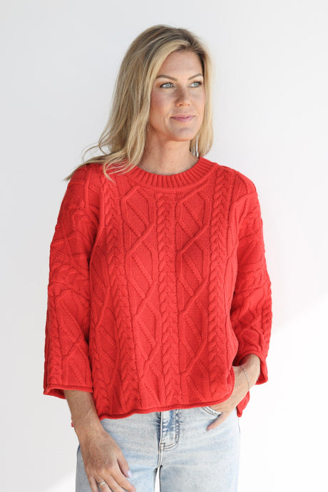 Woman wearing a red cable knit sweater on a white background