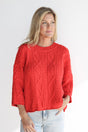 Woman wearing a red cable knit sweater on a white background