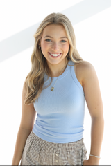 Woman wearing a light blue tank top and plaid skirt on a white background