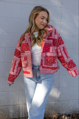 Woman wearing a red and white patterned jacket against a light gray wall.