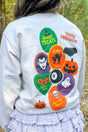 Person wearing a light gray sweatshirt with Halloween-themed graphics outdoors.