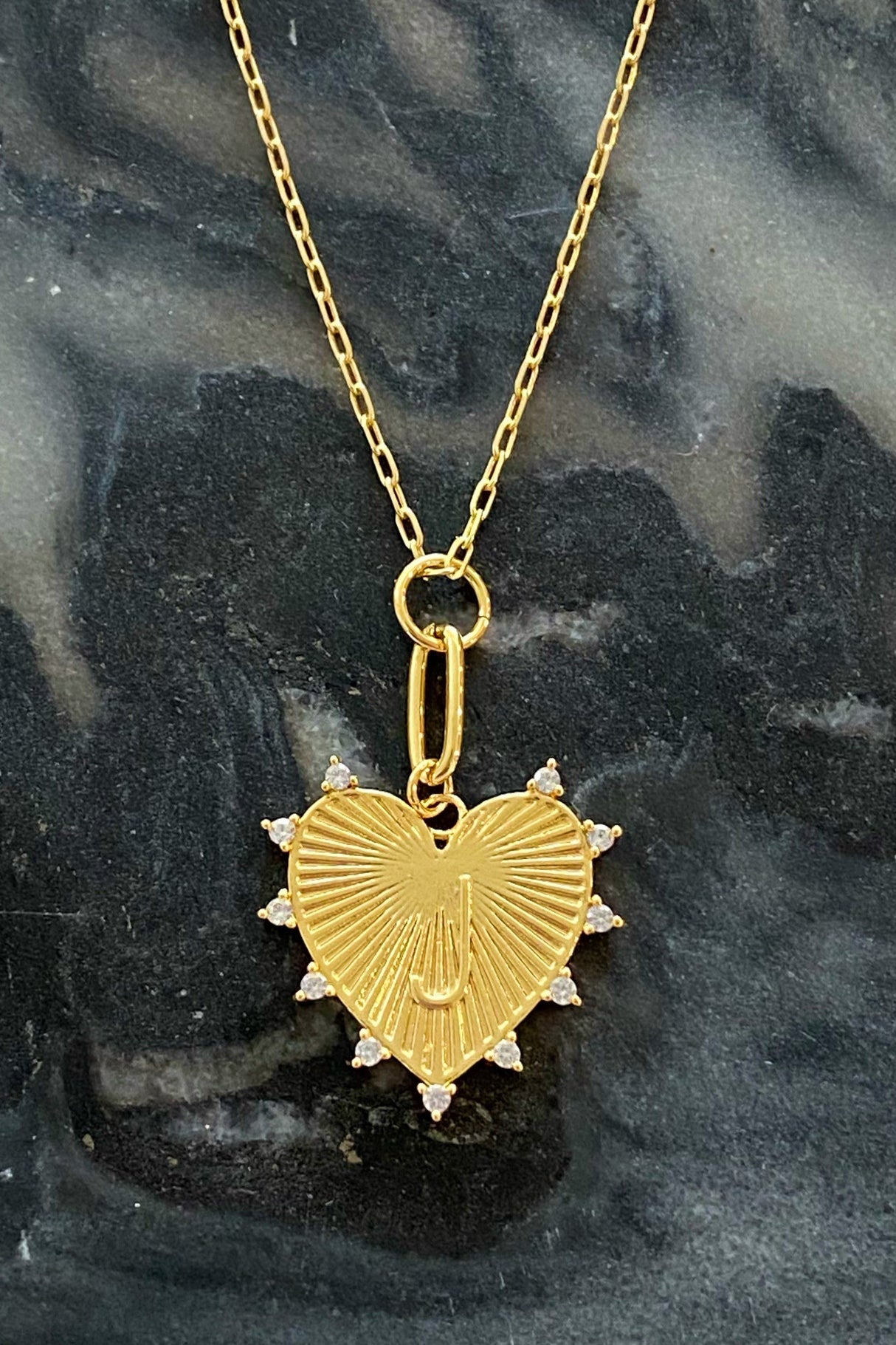 Gold heart-shaped pendant necklace on a dark marble background
