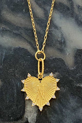Gold heart-shaped pendant necklace on a dark marble surface