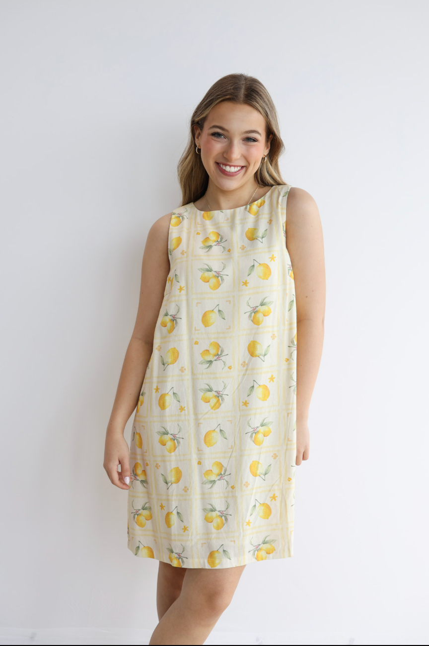 Woman wearing a lemon-patterned dress against a white background