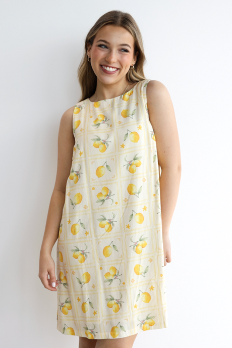 Woman wearing a lemon-patterned dress against a white background