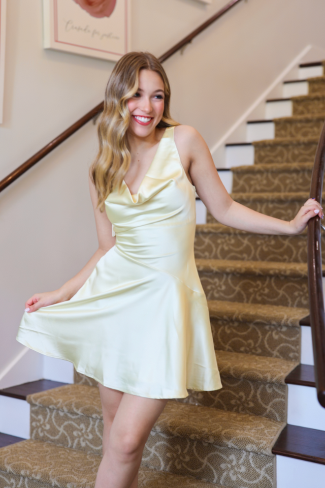 Woman in a light yellow dress standing on a staircase
