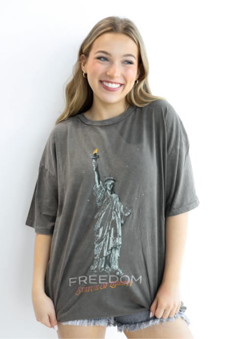 Woman wearing a gray t-shirt with a graphic design of the Statue of Liberty and the word 'Freedom'.