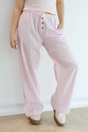Person wearing light pink pants with a white background