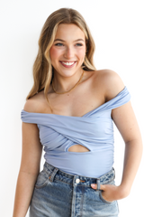 Woman wearing a light blue off-shoulder top and jeans on a white background