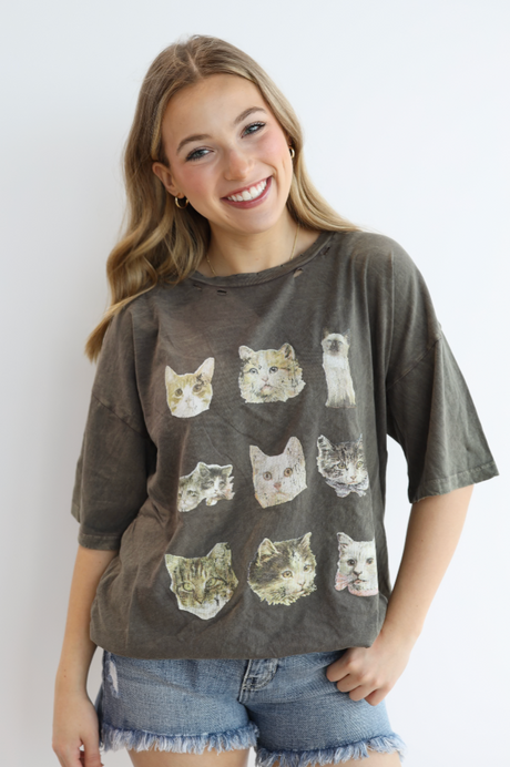 Woman wearing a gray t-shirt with cat prints against a white background