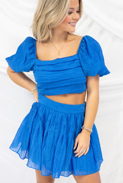 BUDDY LOVE CUTIE SKIRT AND TOP WITH A PUFF SLEEVE AND SOFT PLEAT SKIRT. LAYERING AROUND BUST. AVAILABLE IN BLUE AND PINK.